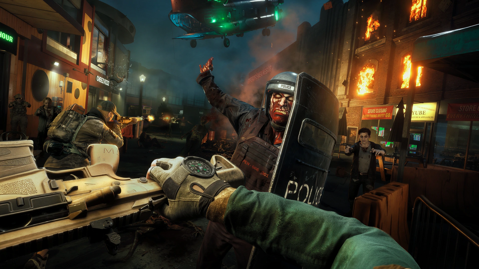 A shield-carrying infected approaches survivors beneath a helicopter on a burning street in No More Room in Hell 2.
